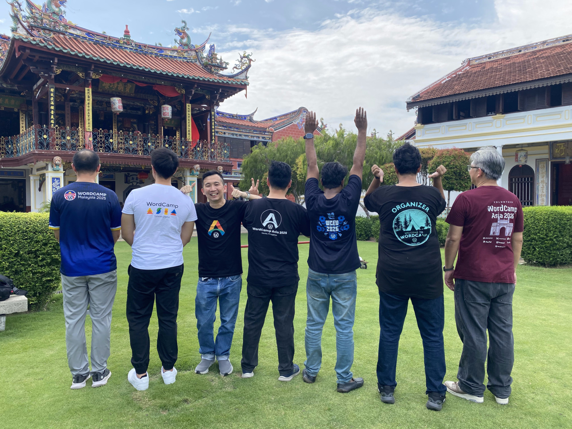 歴代WordCampのTシャツの前で並ぶ下見メンバー